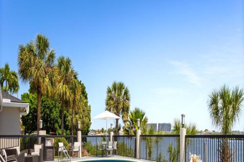 a pool with chairs and a fence with palm trees at Holiday Inn Express Hotel & Suites Tampa-Rocky Point Island by IHG in Tampa