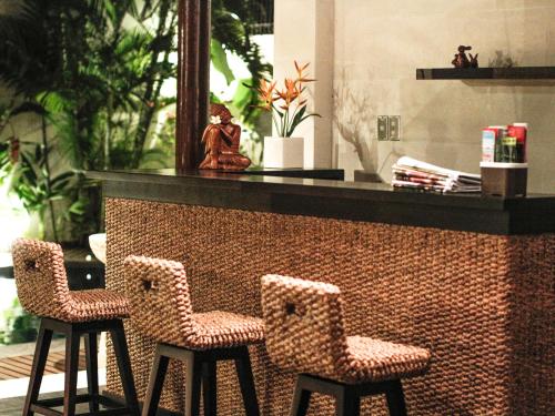 a bar with two chairs and a statue on a counter at Linda Villa Sanur in Sanur