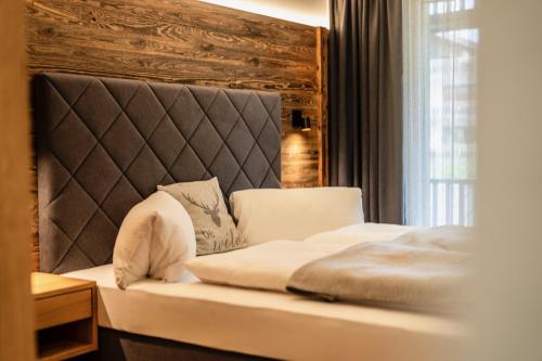 a bedroom with a bed with a headboard and a window at Das Viererspitz 1 - Mittenwald in Mittenwald