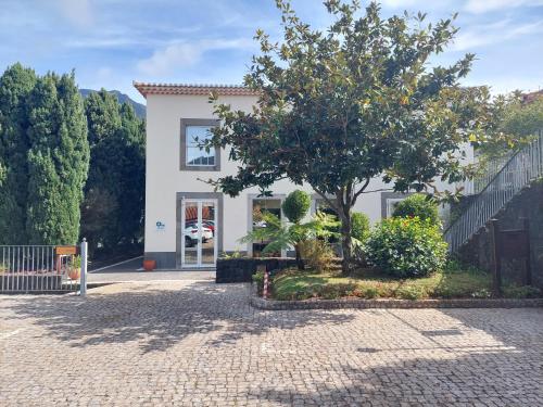 a white house with a tree in front of it at Estalagem do Vale in São Vicente