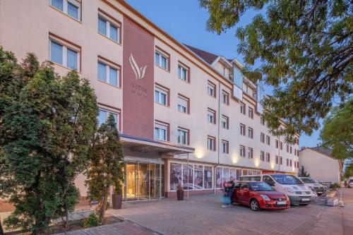 a large building with cars parked in front of it at Vitta Hotel Superior in Budapest