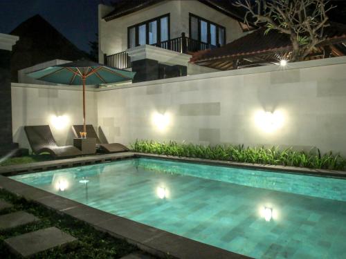 a swimming pool in front of a house at night at Linda Villa Sanur in Sanur