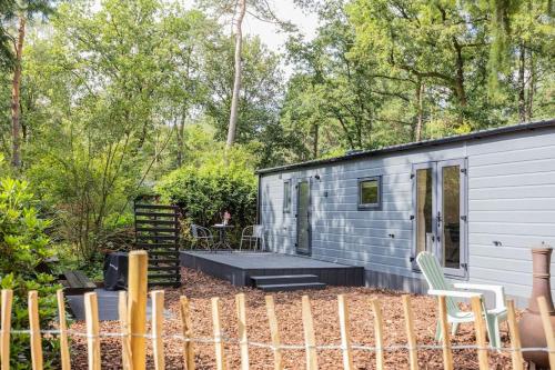 a tiny house in the woods with a porch at Schitterend chalet in het bos in Doornspijk