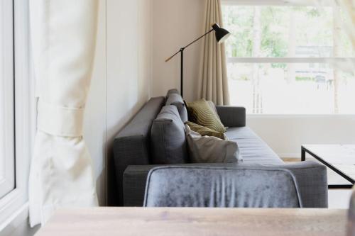 a living room with a gray couch and a window at Schitterend chalet in het bos in Doornspijk