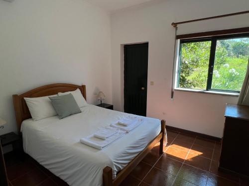 a bedroom with a large white bed with a window at Quinta da Graça Casa do Artista 2 in Resende