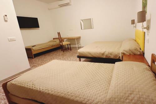 a room with two beds and a table and a chair at Rustico da Pina con angolo cottura in Castions