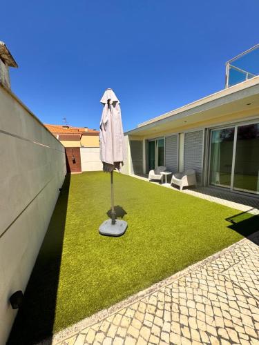 a lawn with an umbrella in the middle of a house at Alfarim House - close to Meco beach and Sesimbra in Sesimbra
