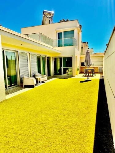a house with a yellow lawn in front of it at Alfarim House - close to Meco beach and Sesimbra in Sesimbra