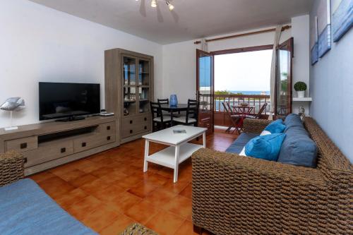 Una sala de estar con un sofá azul y un televisor. en Casa Playa María, en Agaete
