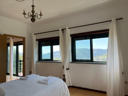 ein Schlafzimmer mit Fenstern und einem Bett mit weißen Laken in der Unterkunft Quinta da Graça Casa do Artista in Resende