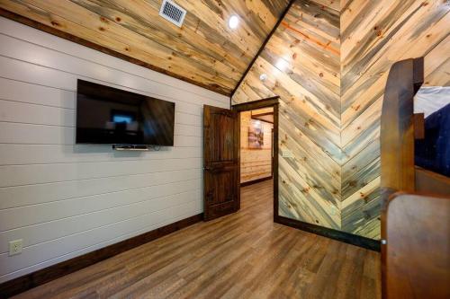 a room with a wooden wall with a television and a bedroom at The Whiskey Trip! Family Getaway in Broken Bow