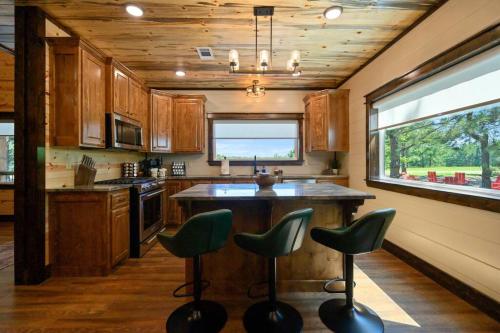 a kitchen with a island with green bar stools at The Whiskey Trip! Family Getaway in Broken Bow