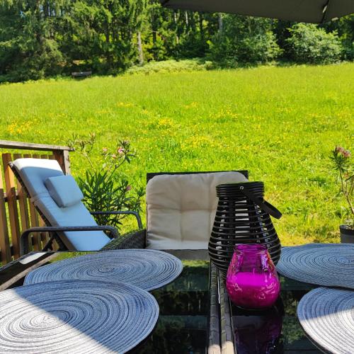 a patio table with a purple vase and a chair at Villa Bischofsberg - Lärchen-Wellness Apartment in Windischgarsten