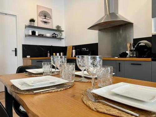 - une table en bois avec des assiettes et des verres dans la cuisine dans l'établissement Havre de confort Bordeaux Chartrons - Cité du vin, à Bordeaux