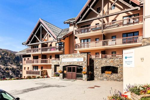 un grand immeuble d'appartements avec un parking dans l'établissement Résidence Le Thabor - maeva Home - Appartement 3 pièces 8 personnes - Sélection MAE-5731, à Le Désert