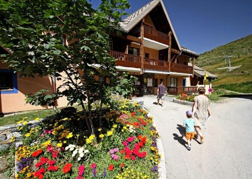 une famille se promenant devant un bâtiment fleuri dans l'établissement Résidence Le Thabor - maeva Home - Appartement 3 pièces 8 personnes - Sélection MAE-5731, à Le Désert