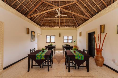 a dining room with tables and chairs and a ceiling at Daima Villas in Jambiani
