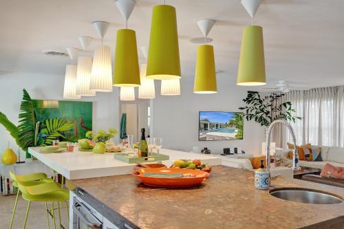 a kitchen with yellow pendant lights above a kitchen counter at New! Waterfront Heated Pool, Fishing Pier, Designer Touches, 2mi to Beach in Fort Lauderdale