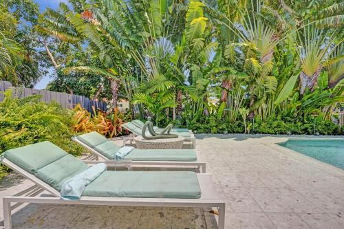 a row of lounge chairs next to a swimming pool at New! Waterfront Heated Pool, Fishing Pier, Designer Touches, 2mi to Beach in Fort Lauderdale