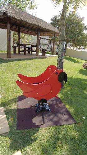 a red bird statue sitting in the grass at Vinhedo Plaza Hotel in Vinhedo