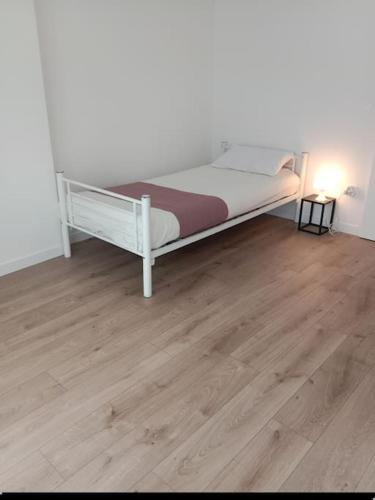 - un lit blanc dans une chambre dotée de parquet dans l'établissement Appartement 3 pièces, à Saint-Denis