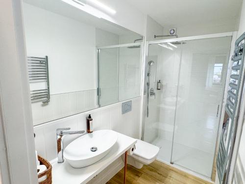 a white bathroom with a sink and a shower at MERSEA in Ustka