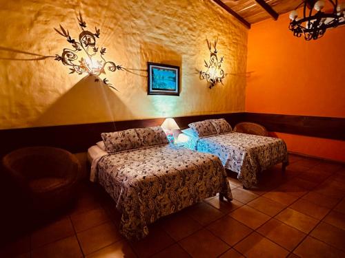 a bedroom with two beds and a chair and lights at El Tejado in Suchitoto