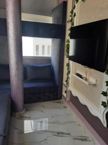 a living room with a couch and a flat screen tv at hermoso apartamento con piscina en marjane in Tetouan