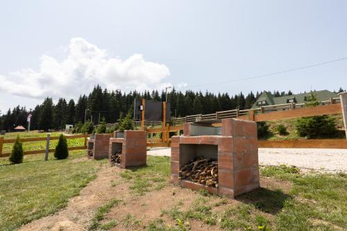 a brick oven in a field next to a fence at Vila Oaza mira Golija in Golija
