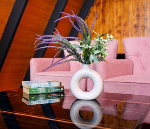 a vase with flowers and books on a glass table at Koro Treehouse Resort Luxury Wooden Cottages and Villas with Private Pool in Kasauli