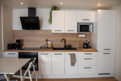 une cuisine blanche avec un évier et un micro-ondes dans l'établissement L'instant Troyen, à Troyes