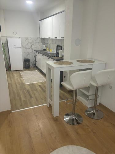 a kitchen with a white table and two bar stools at Apartman Aura in Travnik