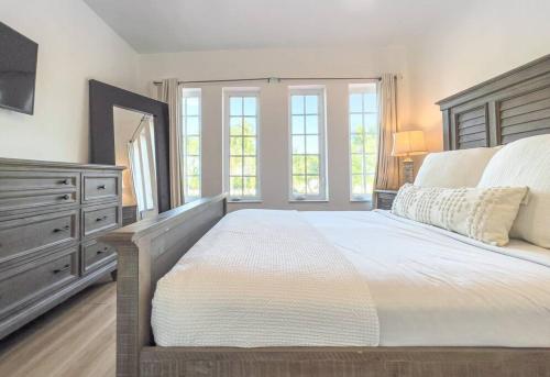 a bedroom with a large bed with a dresser and windows at Ocean Drive apartment w Balcony Walk to the Beach in Miami Beach