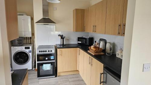 a kitchen with wooden cabinets and a washer and dryer at The Apartment at Brook House in Llanberis