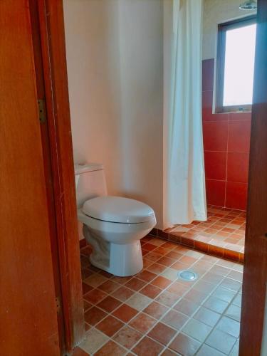 a bathroom with a white toilet and a window at Casa Cactus in San Sebastian Xolalpa