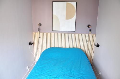 une chambre avec un lit avec une couverture bleue dans l'établissement Le 64 Appartement cosy et calme en Centre-ville, à Charleville-Mézières