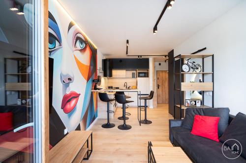 a living room and kitchen with a painting of a woman at Picasso Apartment - Free Parking Place in Sosnowiec
