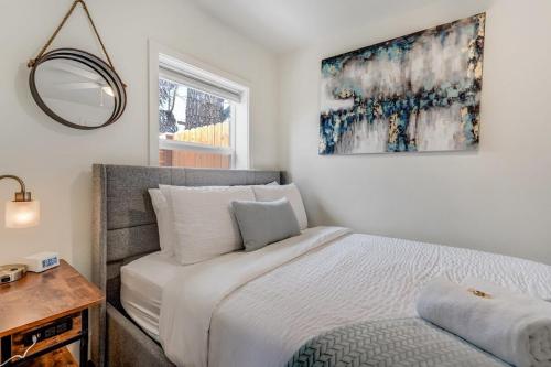 a white bedroom with a bed and a mirror at Baby Blue Cottage Downtown Hot Tub BBQ Fire Pit in Colorado Springs