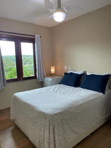 a bedroom with a bed with blue pillows and a window at Guaramiranga Monte Verde in Guaramiranga