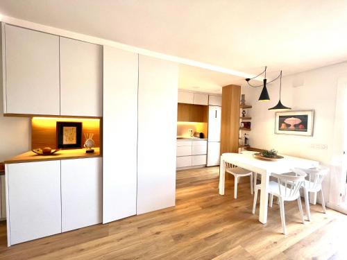 a kitchen and dining room with white cabinets and a table at Ancora Apartment in Vilanova i la Geltrú