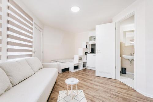 ein weißes Wohnzimmer mit einer Couch und einem Tisch in der Unterkunft Gentilly Apartments Freiberg in Freiberg