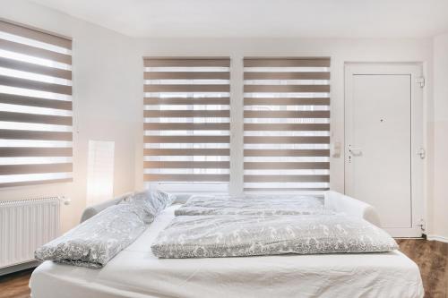 ein weißes Schlafzimmer mit einem großen Bett mit weißer Bettwäsche in der Unterkunft Gentilly Apartments Freiberg in Freiberg