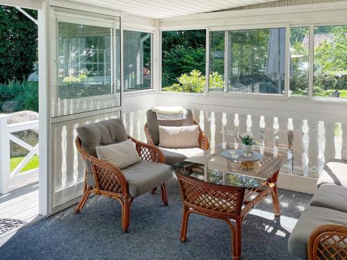 a screened in porch with a glass table and chairs at 5 person holiday home in SÖLVESBORG-By Traum in Sölvesborg