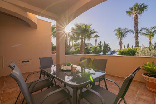 a table and chairs on a balcony with palm trees at Quinta da Boa Nova - Cheerful and spacious 2-bedroom duplex in Estômbar