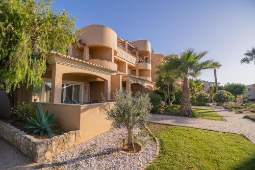a large house with palm trees in front of it at Quinta da Boa Nova - Cheerful and spacious 2-bedroom duplex in Estômbar