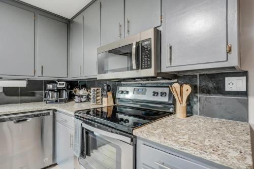 a kitchen with stainless steel appliances and white cabinets at Blackstone Trails Downtown w BBQ & Fire Pit in Colorado Springs