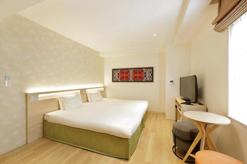 a hotel room with a bed and a television at karaksa hotel Sapporo in Sapporo