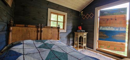 a bedroom with a bed in a room with wooden walls at Rentukka - Sähköttömät Yöpymismökit - Off-grid Cottages in Såris
