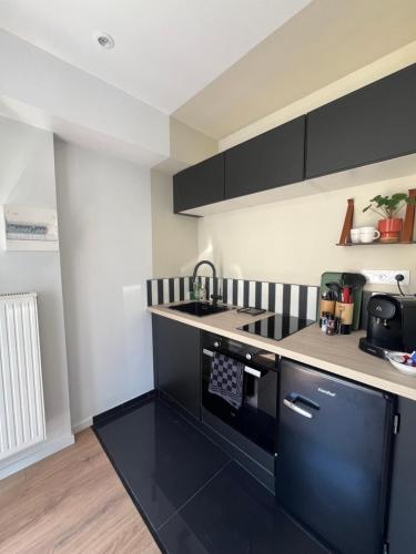 une cuisine avec des armoires noires et blanches et un évier dans l'établissement Studio romantique avec baignoire balnéothérapie duo proche de Colmar et Kaysersberg pour 2 personnes, à Lapoutroie