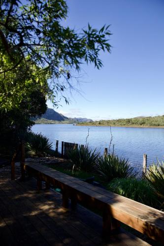 a wooden bench sitting on the side of a lake at Casa Nengueta - Lapinha da Serra in Santana do Riacho